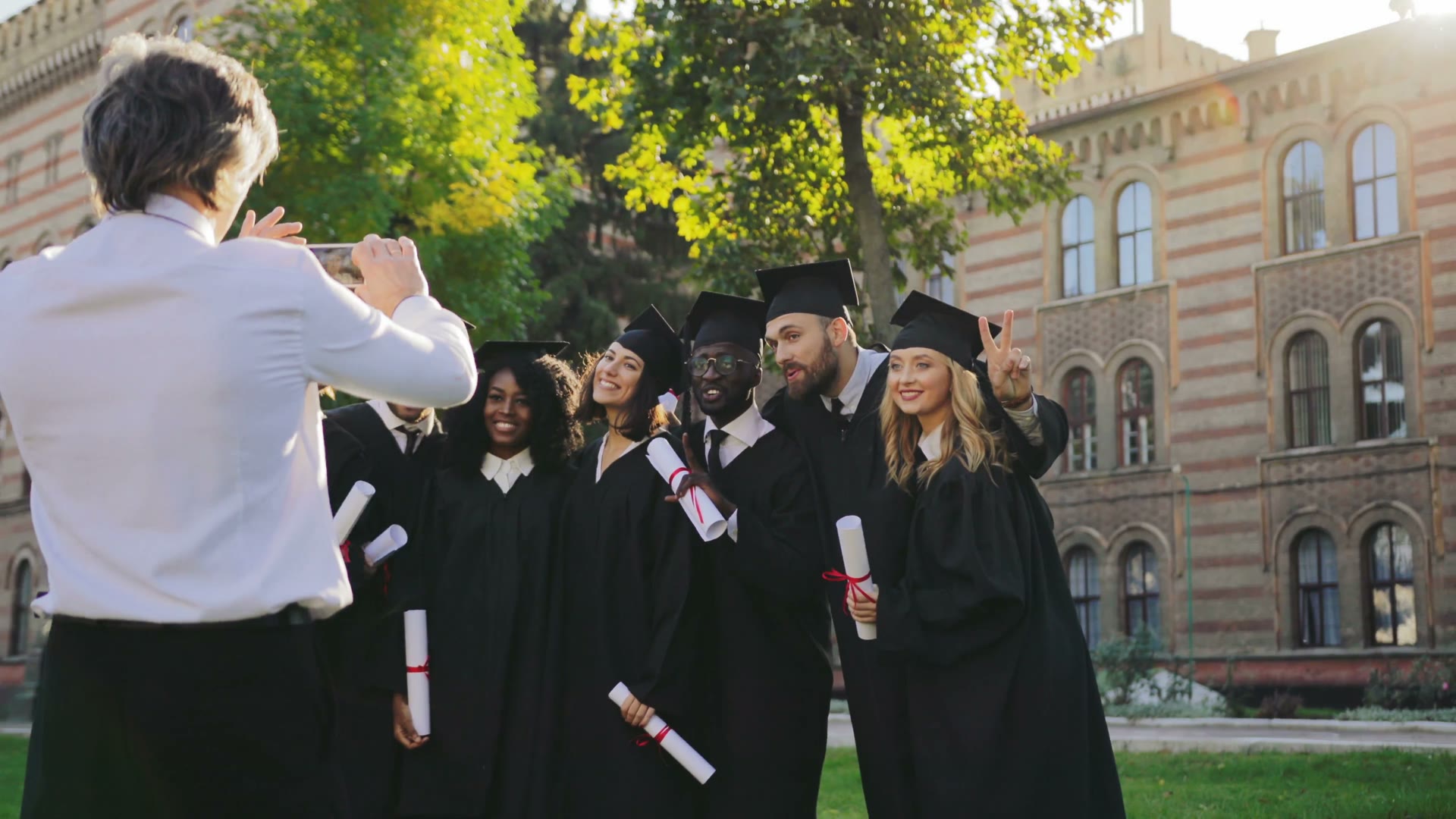 Graduates in caps and gowns posing for a photograph outside a university building